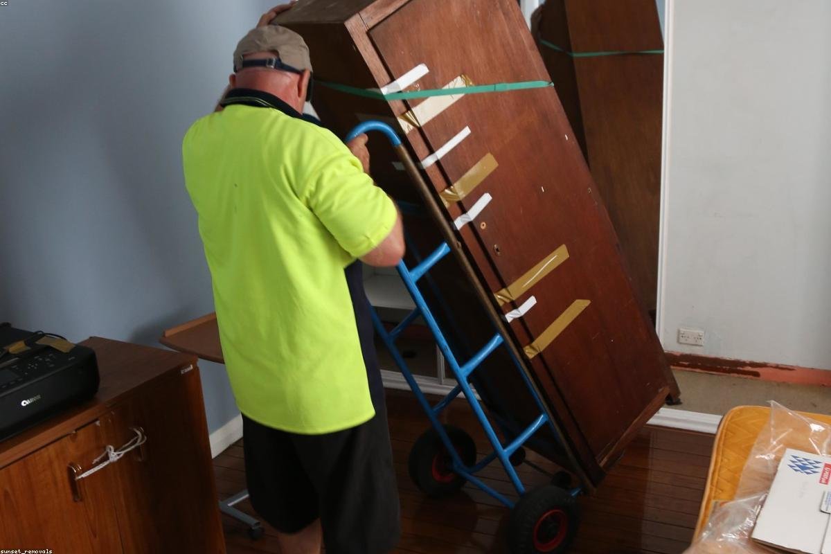 Professional movers carrying a wrapped furniture piece